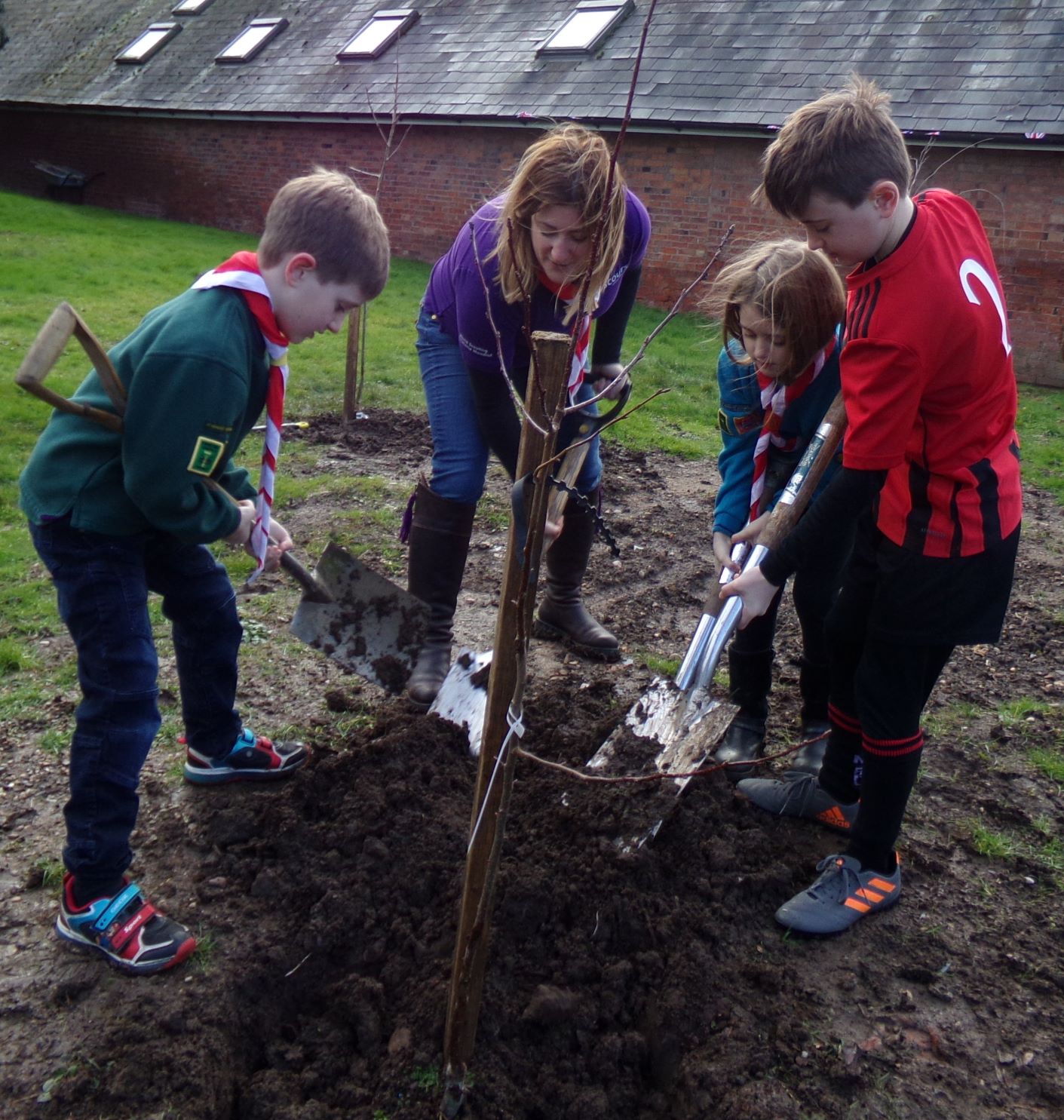 Sienna, Harry and Jonny Morgan planting the crab apple with help from Nicola Morgan